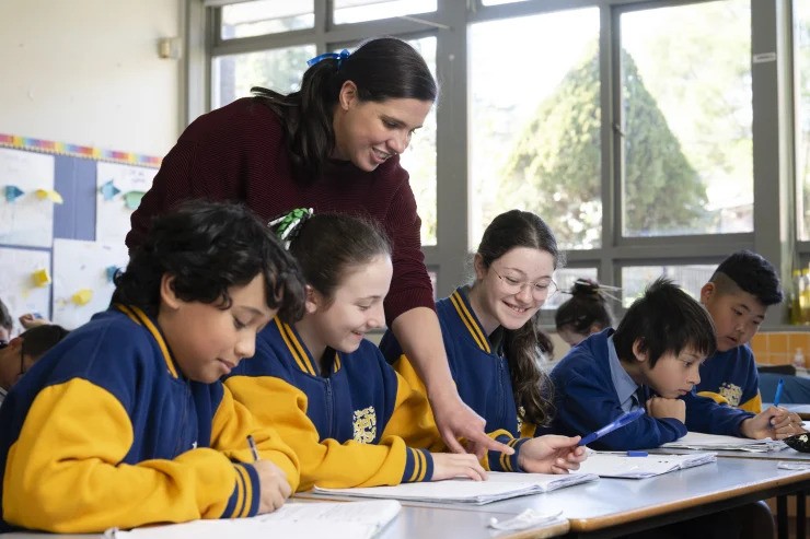 875d1f5ba3dc6595508509a1f69b63ee98788712-ezgif.com-webp-to-jpg-converter A teacher exemplifying one of the 10 essential classroom management skills as her class is focused and organised.